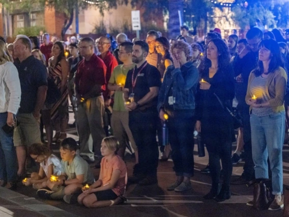 children sitting on curb with adults standing behind them